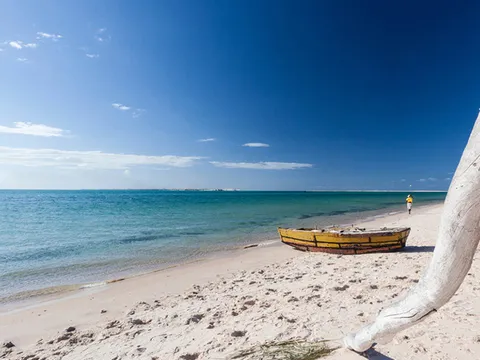 Yellow fishing boat on a deserted white sand beach