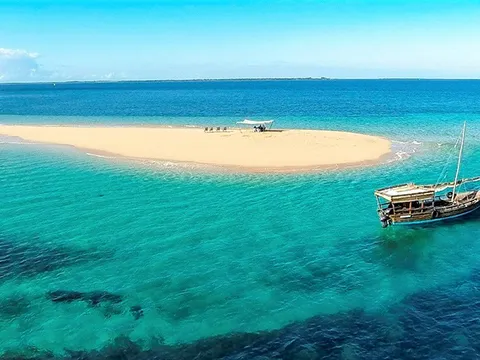 White sandbank in the open sea with a dhow at anchor