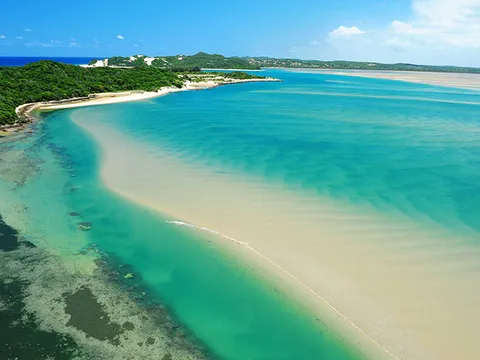 Aerial view of a sand spit and shallow water in several shades of blue